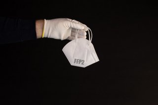 Hand holding medical FFP2 mask on black background